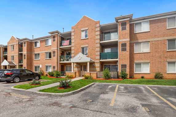 Front view of a three-story brick apartment building with balconies.