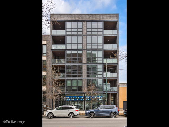 Front view of a modern multi-story building with large glass windows and balconies.