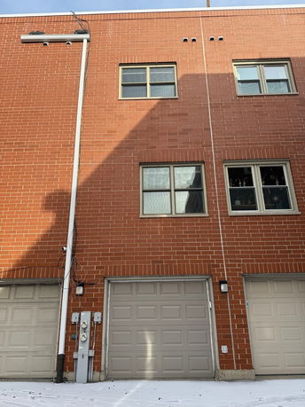 Front view of a brick building with multiple windows and garage doors.
