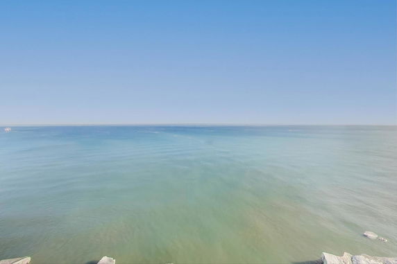 Panoramic view of a vast ocean under a clear blue sky.