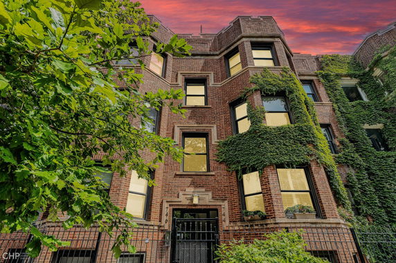Front view of a brick building with ivy and multiple windows.