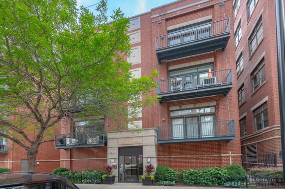 Front view of a multi-story brick building with balconies and an entrance.
