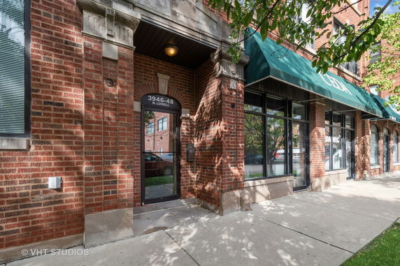 Front view of a brick building entrance with large windows and an awning.