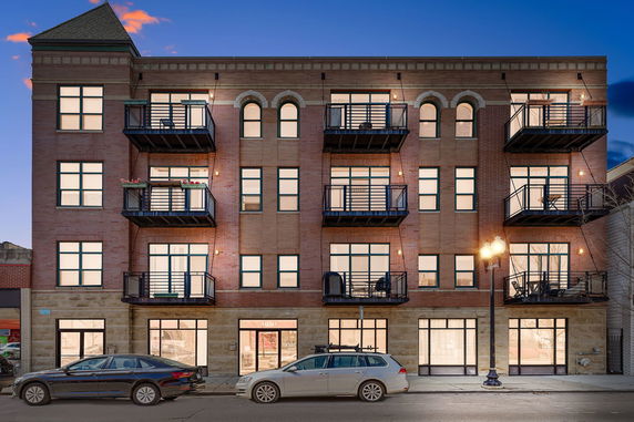 Front view of a multi-story brick apartment building with balconies.