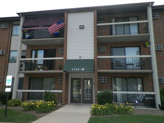 Front view of a three-story apartment building with balconies and an entrance marked 1321-B.