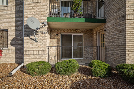 Front view of a brick building with a balcony and satellite dish.