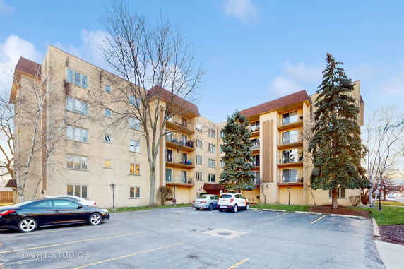 Front view of a multi-story apartment building with a parking area.