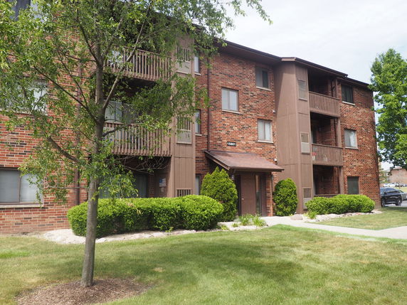 Front view of a multi-story brick apartment building with balconies.