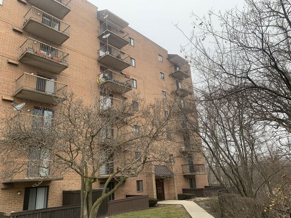 Front view of a multi-story brick apartment building with balconies.