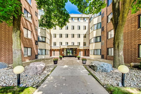 Front view of a multi-story apartment building with brick and panel siding.