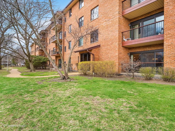 Front view of a multi-story brick residential building with balconies.