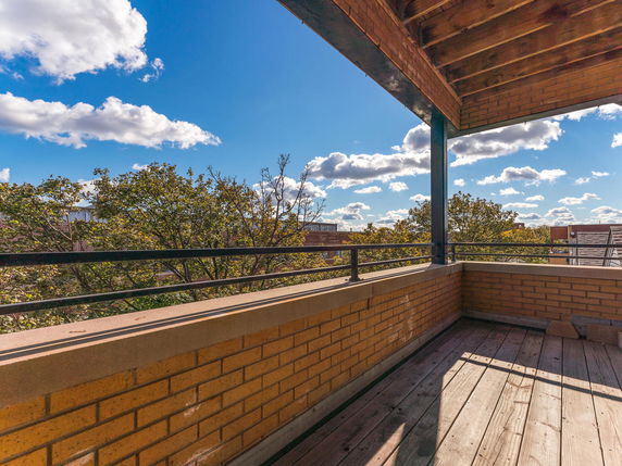 View from a balcony overlooking trees and a clear blue sky.
