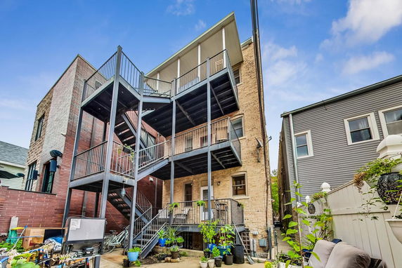 Rear view of a multi-story residential building with outdoor staircases and balconies.
