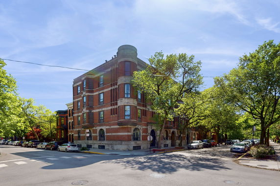 Street view of a multi-story brick building with arched windows and decorative stone trim.