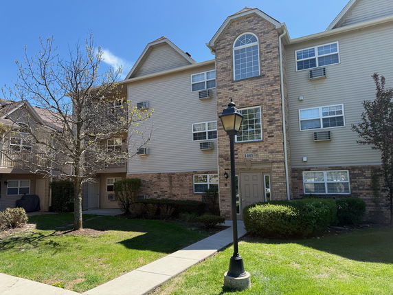 Front view of a multi-story residential building with brick and siding exterior.
