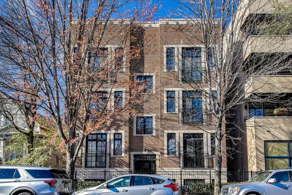 Front view of a multi-story brick building with large windows.