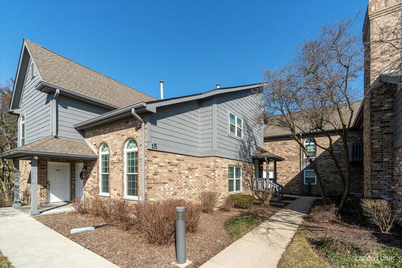 Front view of a multi-story brick house with a gable roof and arched windows.
