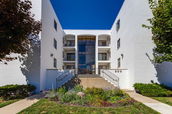 Front view of a multi-story residential building with balconies and large glass entrance.