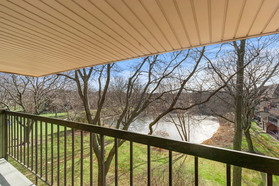 Panoramic view from a balcony showing trees and a body of water.