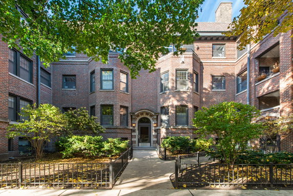 Front view of a multi-story brick building with bay windows and decorative entrance.