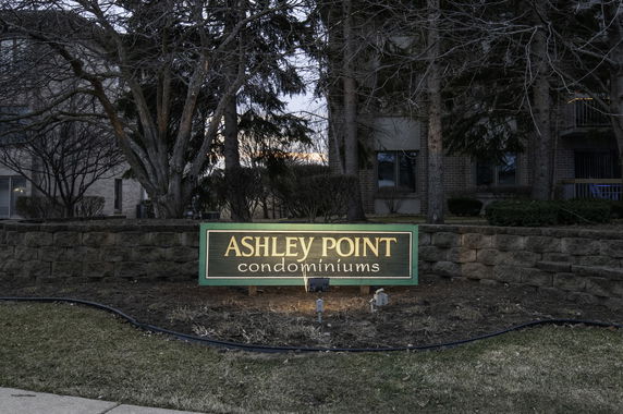 Front view of Ashley Point condominiums with building partially visible behind a sign.