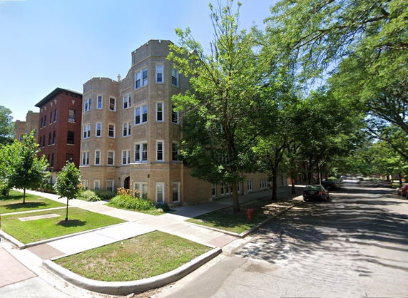Front view of a multi-story brick building on a tree-lined street.