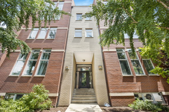 Front view of a multi-story brick building with large windows and entrance stairs.