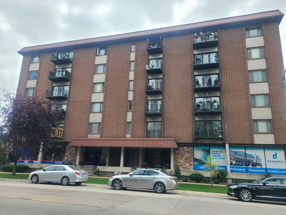 Front view of a multi-story brick residential building with balconies.