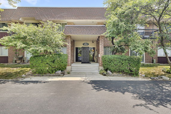 Front view of a two-story building with a main entrance flanked by greenery.
