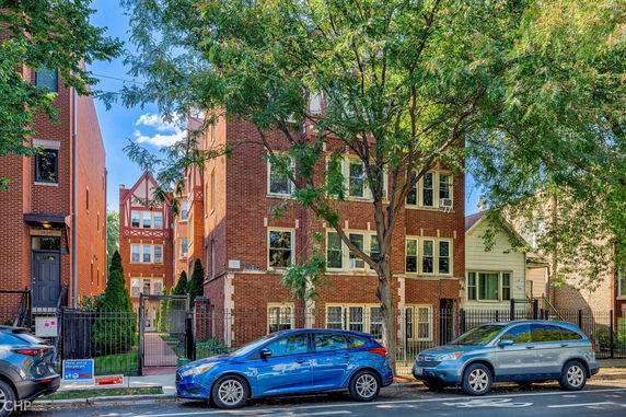 Front view of a multi-story brick building with tree-lined street.