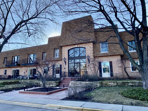 Front view of a multi-story brick building with balconies and a central entrance.