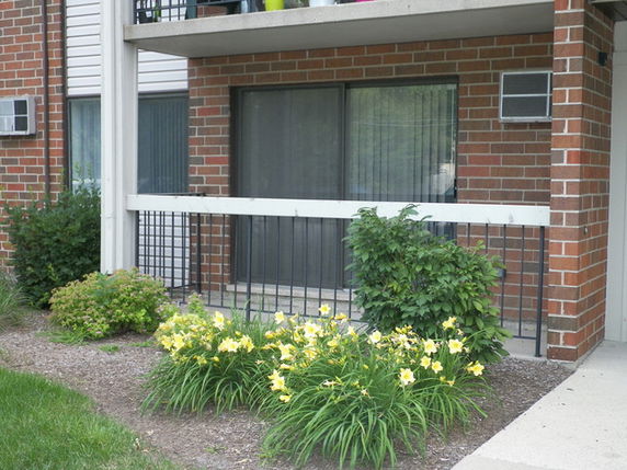 Front view of an apartment building with brick facade and a garden.
