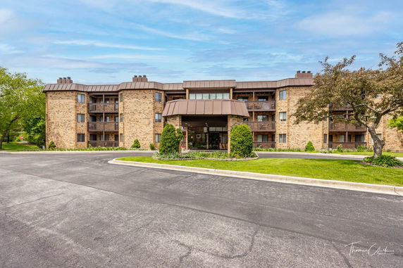 Front view of a multi-story brick building with balconies and a central entrance.