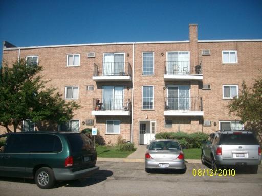 Front view of a three-story brick apartment building with balconies.