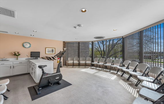 Interior view of a room with exercise equipment and chairs arranged around the perimeter.