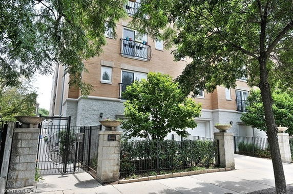 Front view of a multi-story residential building with a gated entrance.