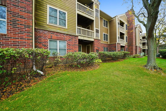 Front view of a multi-story apartment building with brick and wooden exterior.