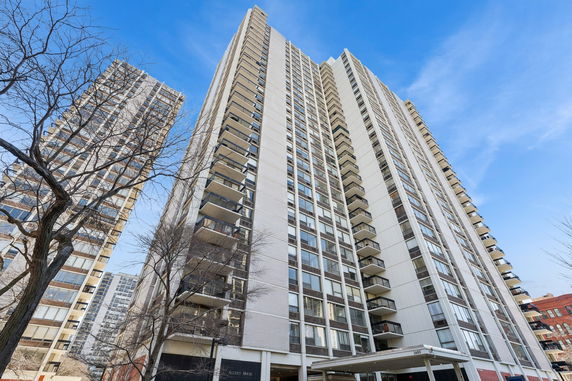 Front view of a tall residential building with balconies and large windows.