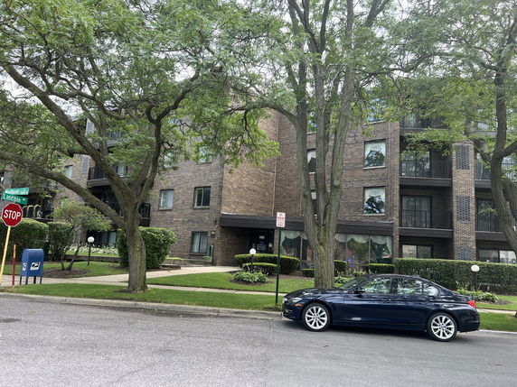 Front view of a multi-story brick apartment building with balconies.