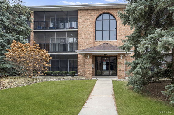 Front view of a three-story brick apartment building with balconies and a central entrance.