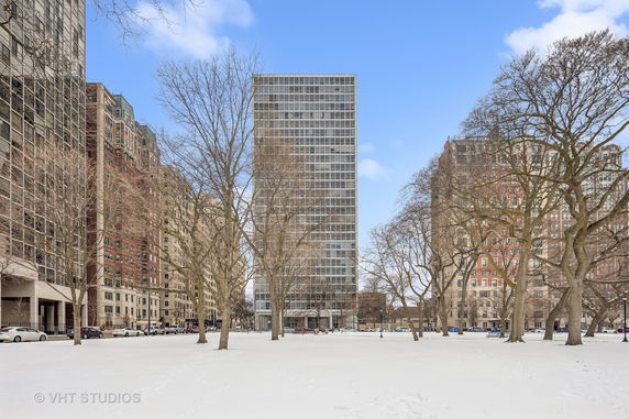 Front view of a high-rise building with a glass facade in a snowy urban setting.