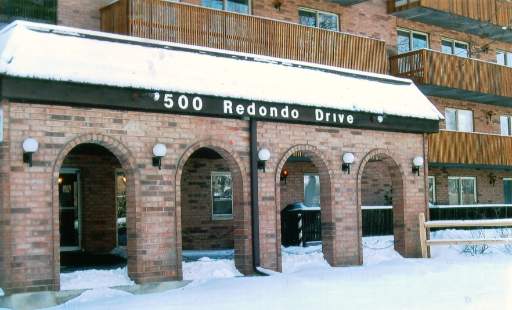 Front view of a multi-story brick building with balconies and snow-covered entrances.