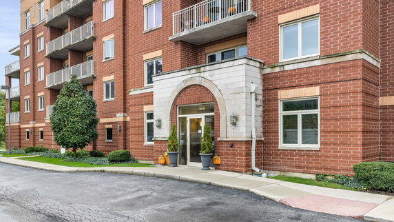 Front view of a multi-story brick apartment building with balconies.
