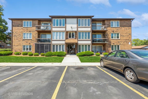 Front view of a three-story apartment building with brick exterior and balconies.