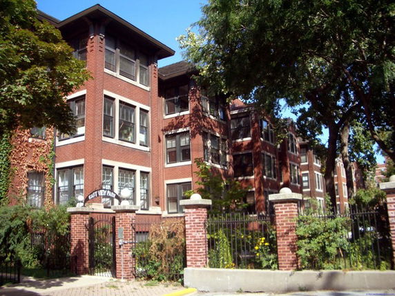 Front view of a multi-story brick apartment building with large windows.