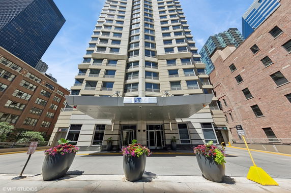 Front view of a multi-story building entrance with a canopy and planters.