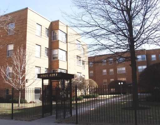 Front view of a multi-story apartment building with a gated entrance.