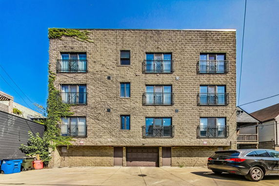 Front view of a multi-story building with balconies and a garage.