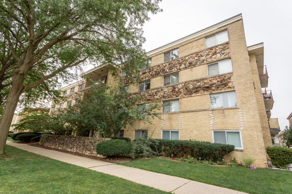Front view of a multi-story apartment building with brick facade and stone accents.
