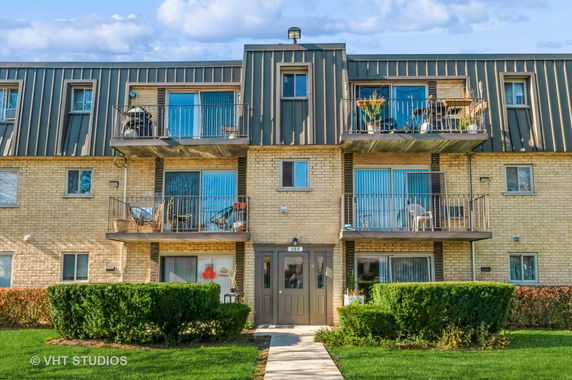 Front view of a three-story apartment building with balconies and a central entrance.
